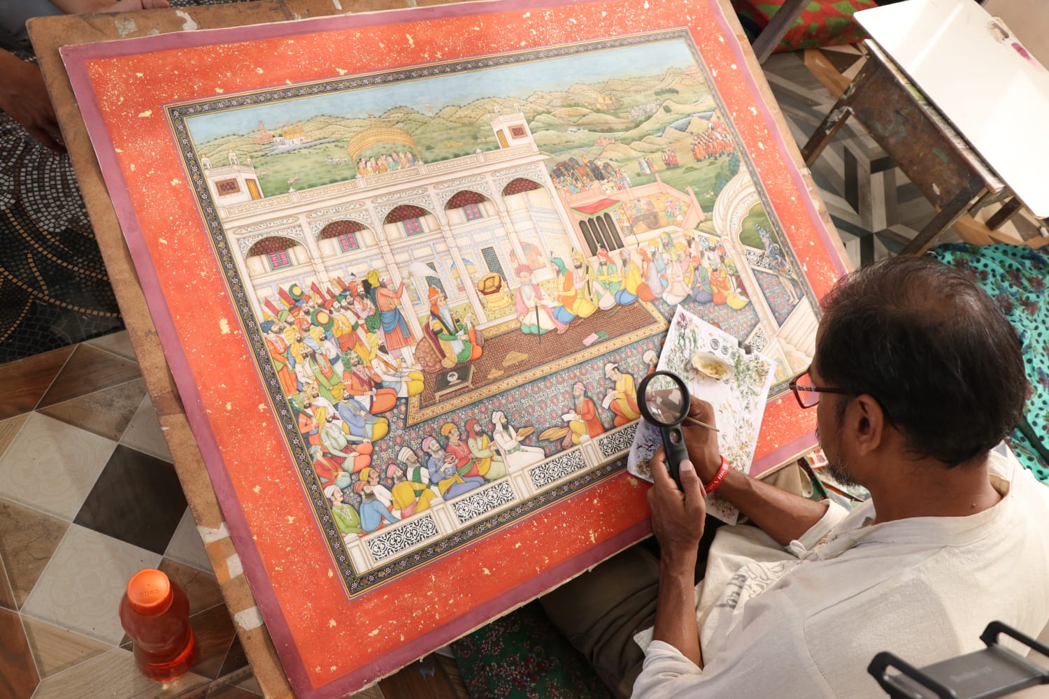 A miniature painter carefully studying a richly detailed painting at work